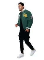 Hombre con chamarra beisbolera verde, pantalones negros y tenis blancos